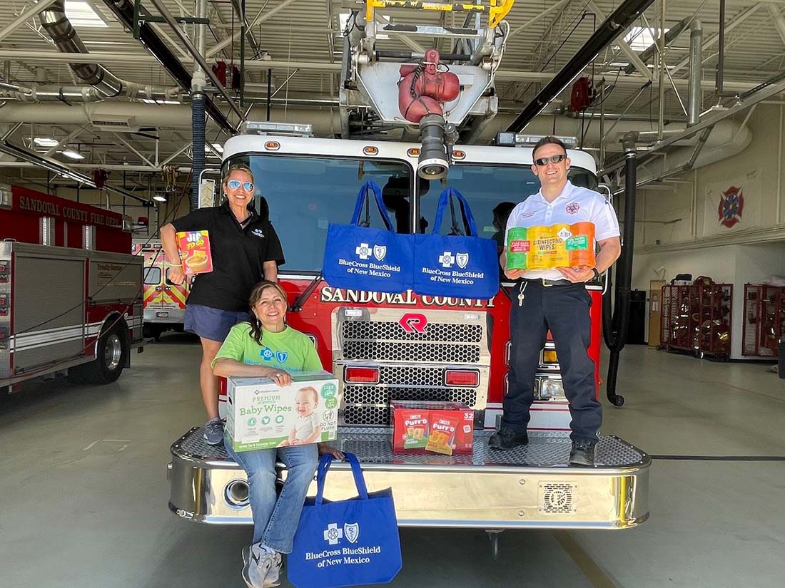 BCBSNM and Sandoval County Fire and Rescue employees stand on a fire truck with donated supplies