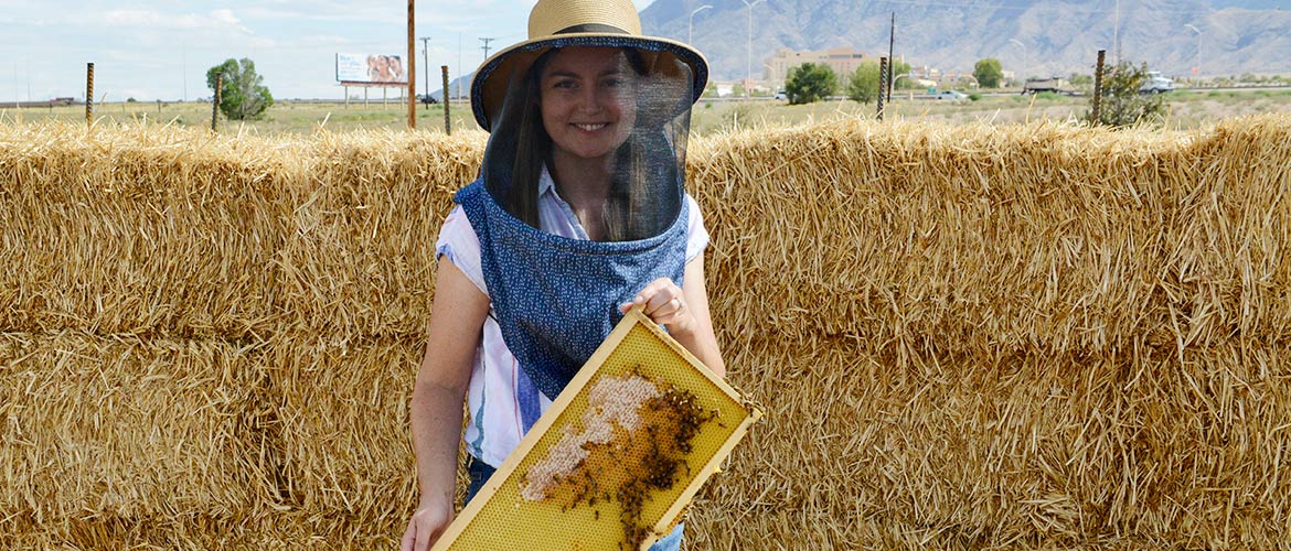 A beekeeper poses with beehive frame.