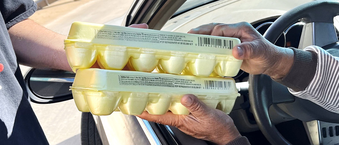 Egg cartons are handed to someone sitting in the driver's seat of a vehicle