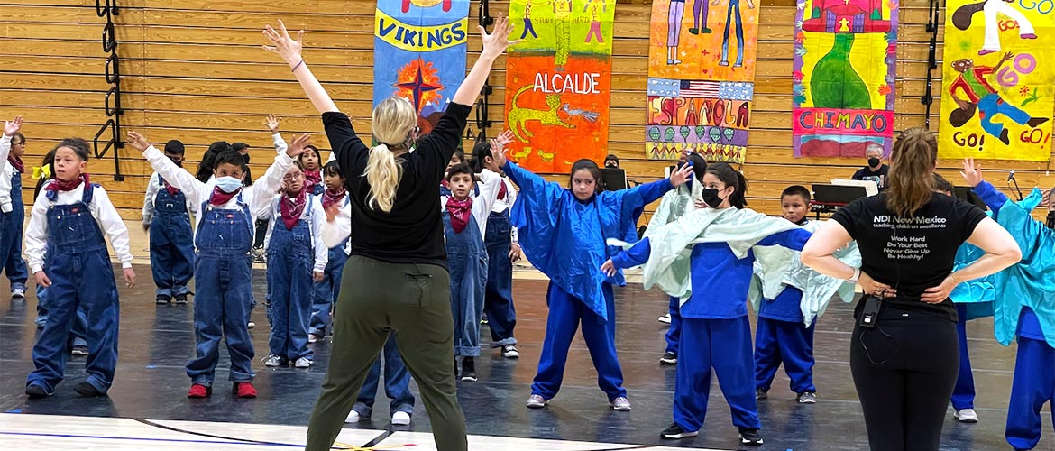 Instructor teaches dance moves to a group of schoolchildren. 