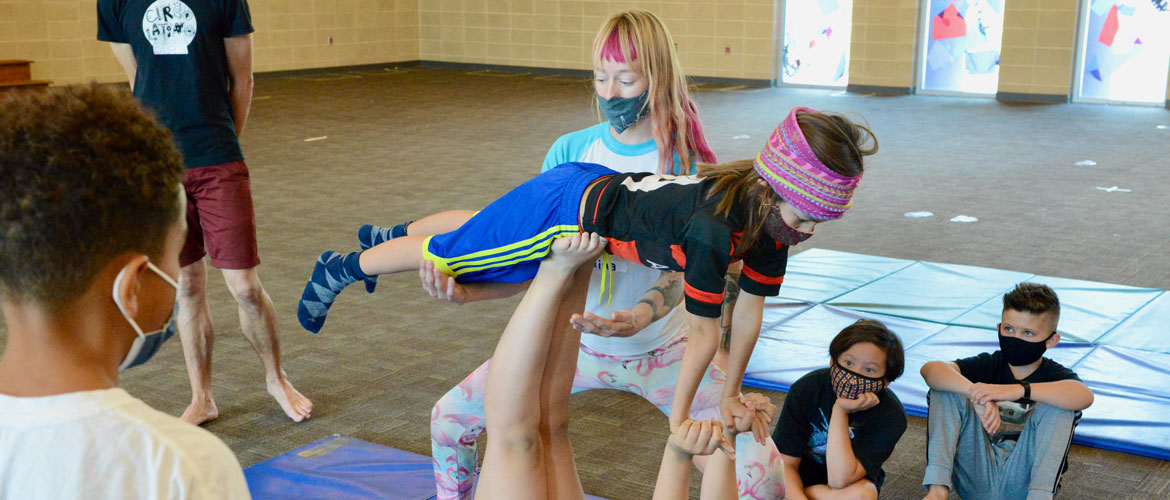 Children practice acro-balance in circus arts program. 