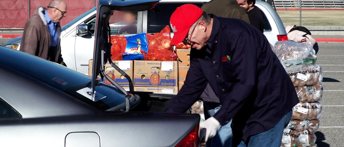 A food bank volunteer loads boxes into cars