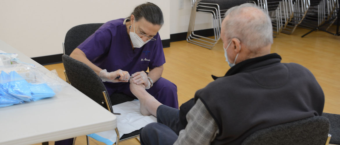 An older adult receives nail trimming services.. 