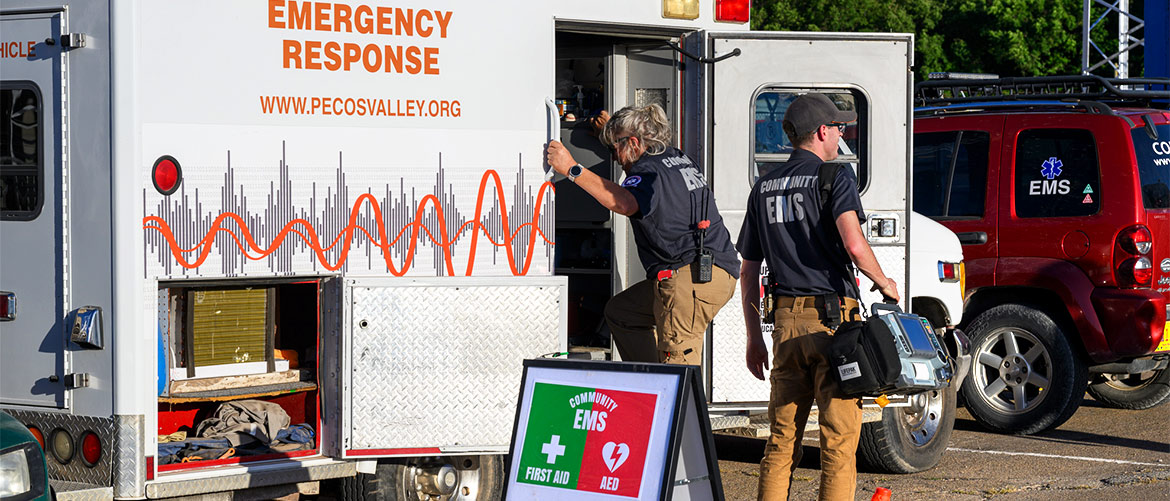 An older emergency worker climbs into a white ambulance while another looks to his right