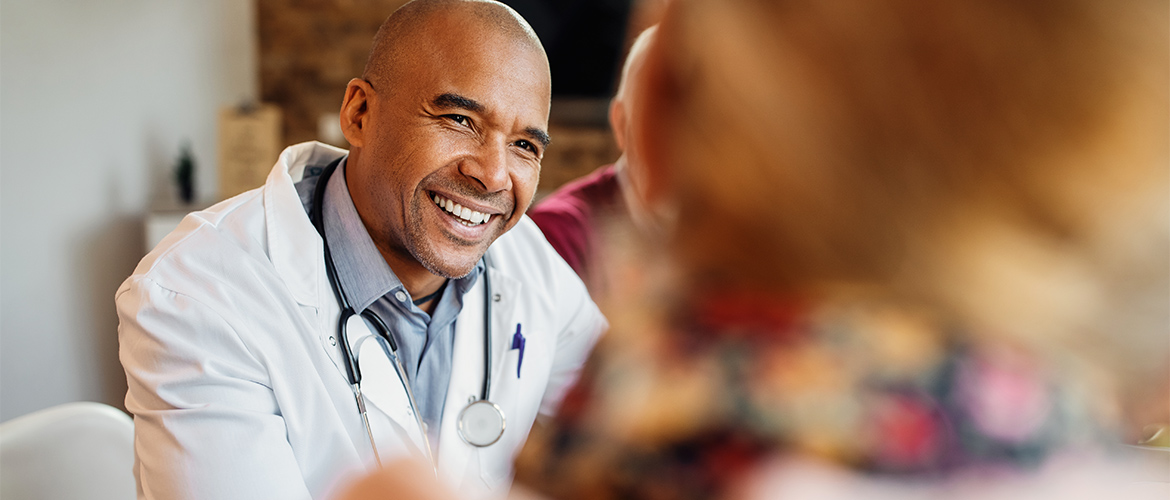 A doctor smiles as he sits