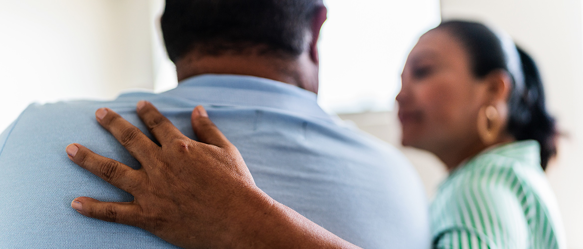 Woman with tan complexion comforts man in blue shirt