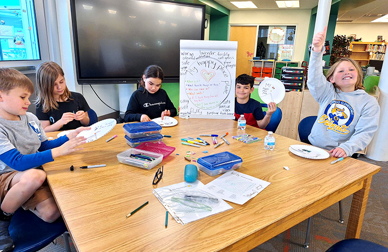 Children sitting around a table create artwork