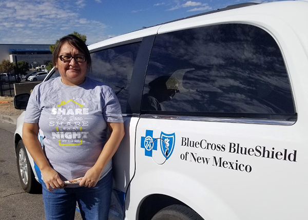 BCBSNM 2020 Volunteer of the Year Mary Charley stands next to a van with the BCBSNM logo.