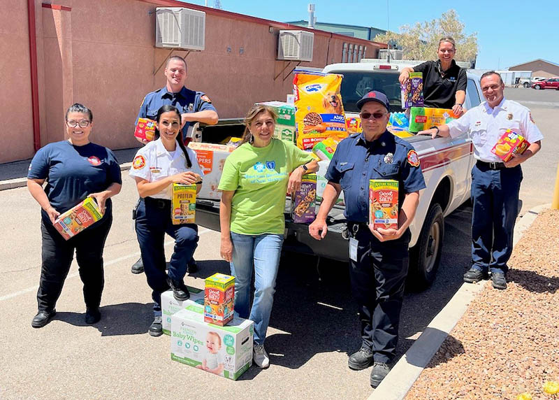 BCBSNM and Rio Rancho Fire and Rescue employees stand with pickup truck loaded with donated supplies. 
