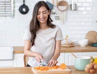 Woman chopping carrots in a kitchen