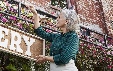 Small Business Owner hangs a sign for her bakery