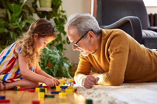 Abuelo y nieta juegan con Legos en el suelo