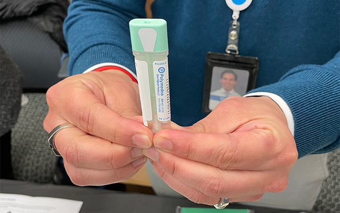 Un empleado de BCBSNM sostiene una prueba de detección de cáncer colorrectal en el hogar.