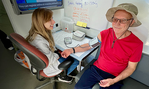 Médica le toma la presión arterial a un hombre mayor.
