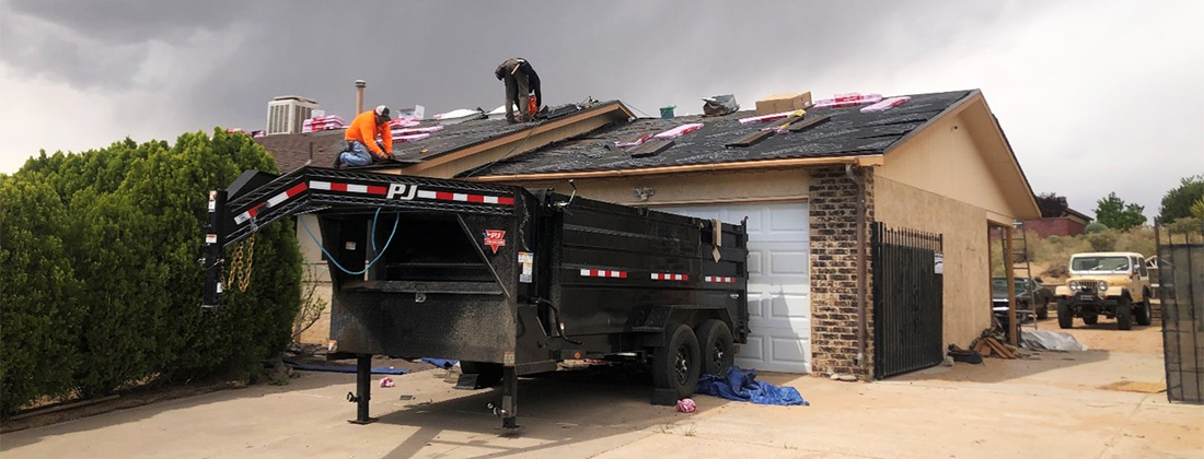 Dos hombres reparan el techo de una casa.
