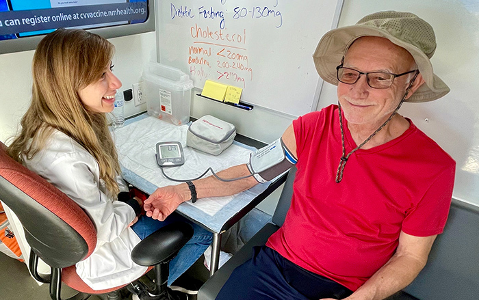 A woman clinician takes the blood pressure of an older man. 