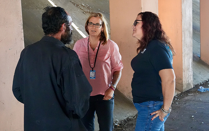 Two care coordinators talking with homeless man