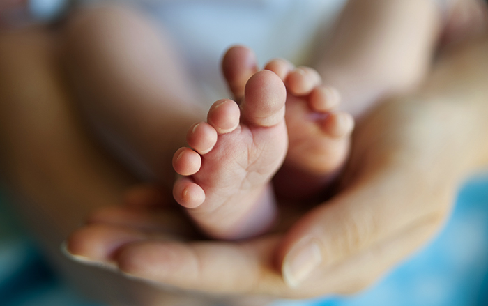 Una mamá acaricia los dedos de los pies de su bebé