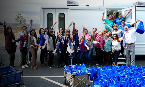 Employees pose in front of Care Van® with donation packages