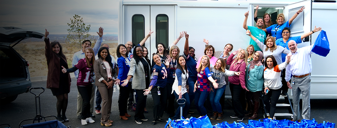 Employees pose in front of Care Van® with donation packages