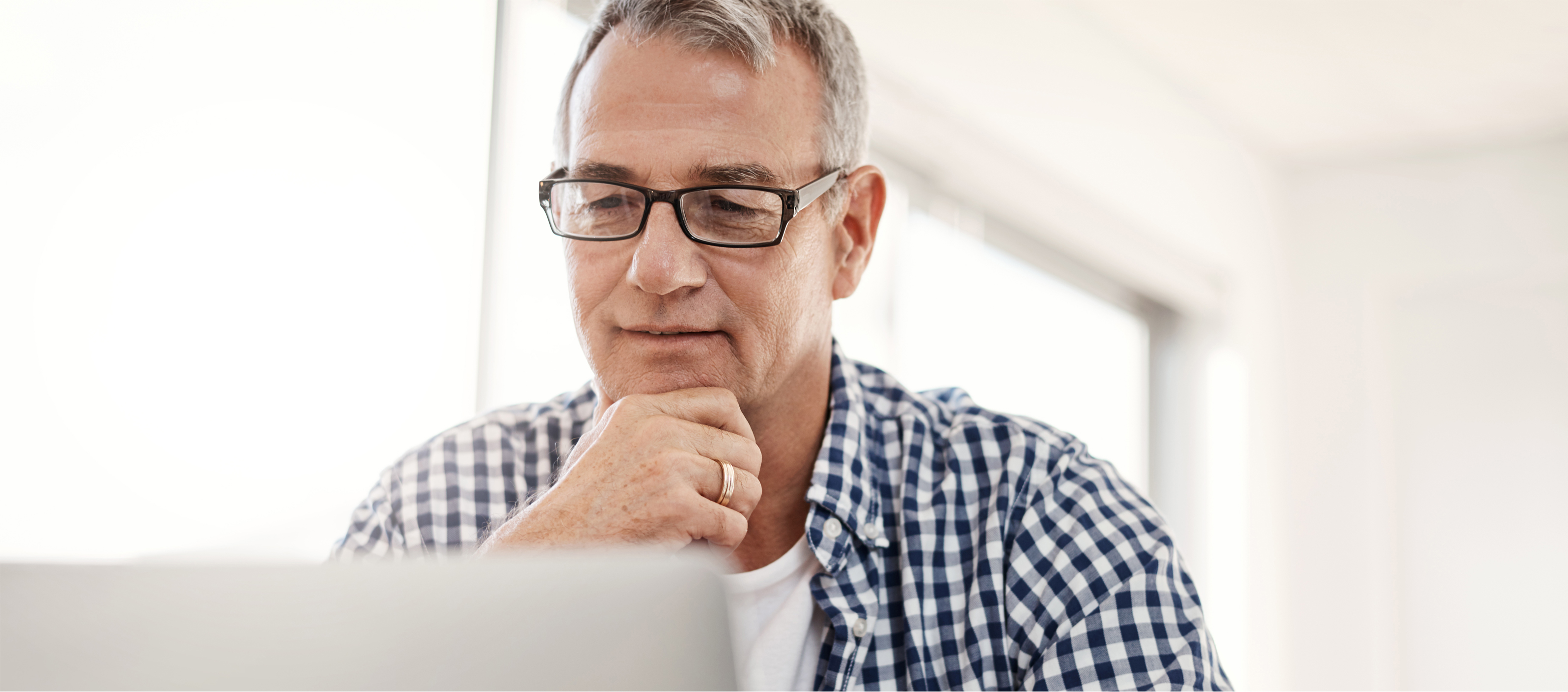 A man wearing glasses looking at computer screen